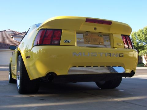 2002 Ford Mustang - Rear view of a yellow 2002 Ford Mustang GT, showing the distinctive taillights and dual exhaust pipes.