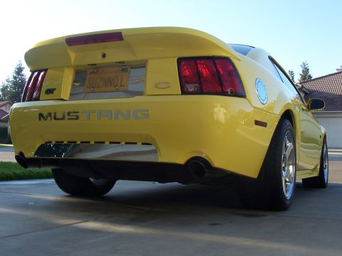 2002 Ford Mustang - Rear view of a yellow 2002 Ford Mustang GT showing the taillights, spoiler, and exhaust pipes.