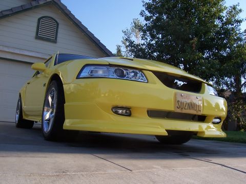 2002 Ford Mustang - A yellow 2002 Ford Mustang is parked in front of a house. The license plate is visible.