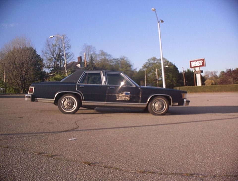 Dark blue four-door sedan in side profile on an empty parking lot with a BB&T sign behind