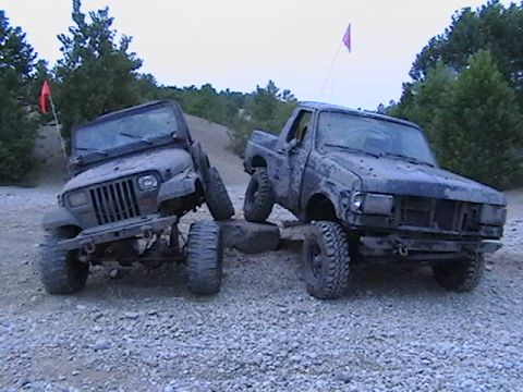1988 Ford Bronco - Two off-road vehicles, a Jeep Wrangler and a Ford F-Series truck, navigate a challenging rocky landscape.