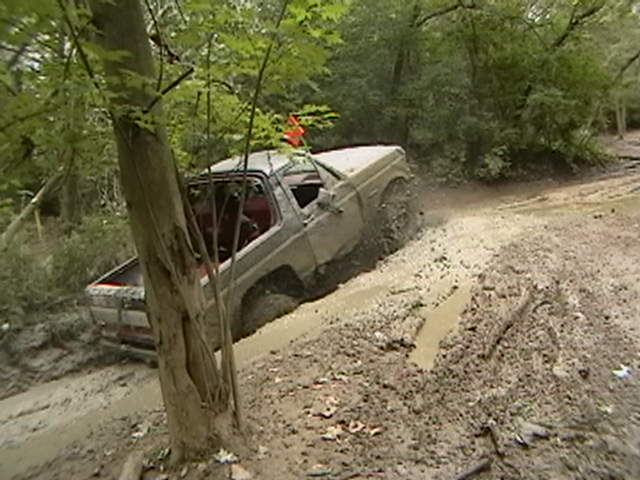 1988 Ford Bronco navigating a muddy trail, kicking up dirt