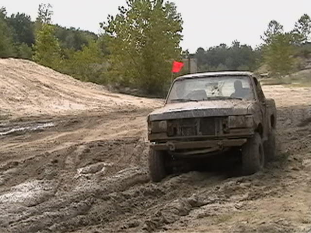 1988 Ford Bronco driving through mud, front view