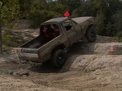 1988 Ford Bronco - Pickup truck navigates an off-road obstacle course on a sandy terrain.
