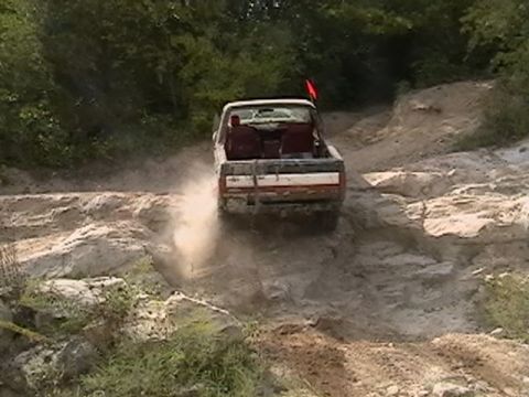 1988 Ford Bronco - A pickup truck kicks up dust as it navigates a challenging off-road trail.