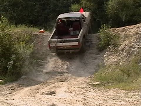 1988 Ford Bronco - An older model truck navigates a steep, dusty incline on a dirt track.