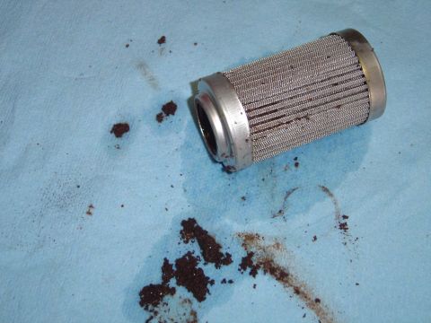 1978 Ford Bronco - A used oil filter, showing debris and metal mesh, rests on a blue shop towel.