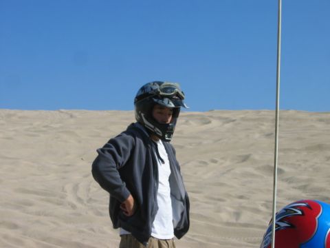 1985 Ford Bronco - A person stands in a sandy landscape under a clear blue sky, with a flag pole and a vehicle visible.