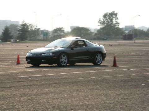 2001 Mercury Grand Marquis - A black coupe navigates a course marked by traffic cones, with the Supermotors.net logo in the lower right corner.