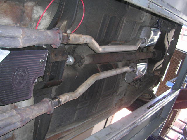 Undercarriage of a 1975 Ford Ranchero showing dual exhaust pipes and chrome mufflers