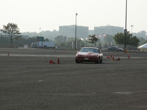 2001 Mercury Grand Marquis - A red Pontiac Firebird Trans Am navigates a course marked by traffic cones in an open lot.