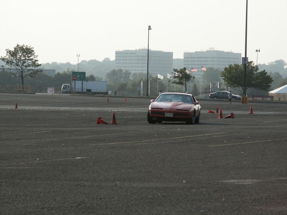 Red Pontiac Firebird Trans Am driving through cones on a track