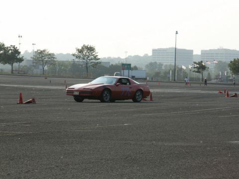 2001 Mercury Grand Marquis - A red sports car navigates a course marked by orange cones in an open lot.