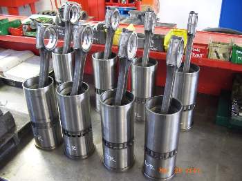 1994 Ford F-150 - Engine pistons and connecting rods are displayed on a workbench, possibly for repair or inspection.