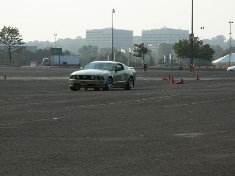 2001 Mercury Grand Marquis - Gold Ford Mustang participating in an event with orange cones set up in a parking lot.