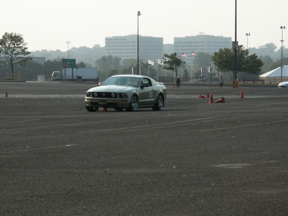 Gold Ford Mustang in a parking lot with orange cones