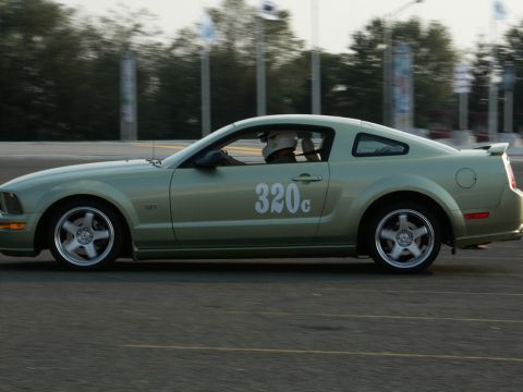 2001 Mercury Grand Marquis - A light green Ford Mustang with racing number 320c is captured in motion on a track.