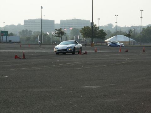 2001 Mercury Grand Marquis - A silver Chevrolet Camaro navigates a course marked by orange cones, with buildings visible in the distance.