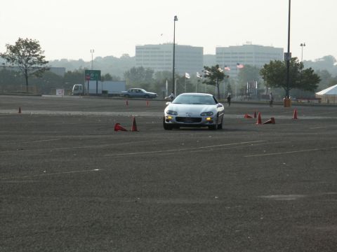 2001 Mercury Grand Marquis - A silver sports car navigates a course marked by traffic cones, with buildings in the background.