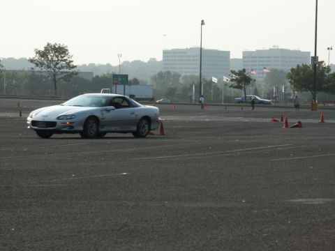 2001 Mercury Grand Marquis - Silver Chevrolet Camaro navigates a course marked by orange cones on a paved lot.