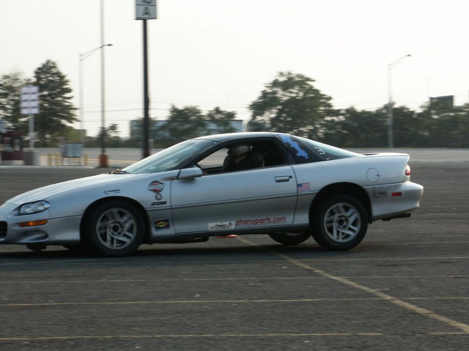 Silver Chevrolet Camaro Z28 driving on a track. Has a Z28 badge and 'stranoparts.com' sticker