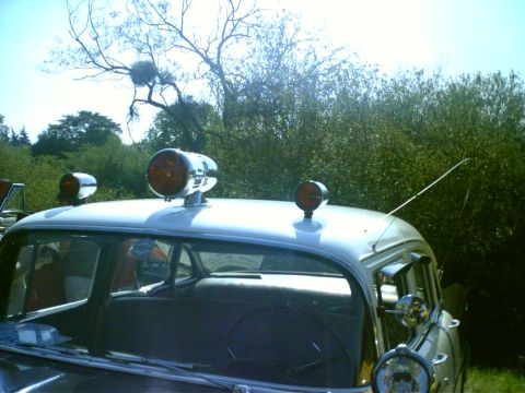 1991 Ford Crown Victoria - A vintage police car is seen from the side with amber lights mounted on its roof.