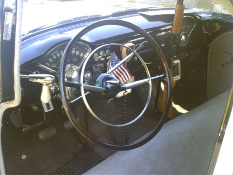 1991 Ford Crown Victoria - The interior of a classic car features a large steering wheel, dashboard gauges, and small American flags.