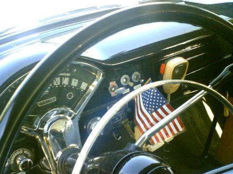 1991 Ford Crown Victoria - The interior of a classic car features a prominent steering wheel, dashboard gauges, and a small American flag.