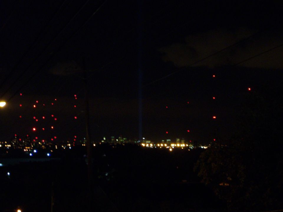 Night skyline with city lights and numerous red lanterns floating in the sky