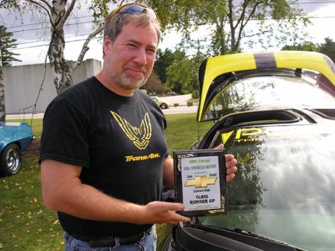 1994 Pontiac Trans Am - A man proudly displays his trophy next to a 1998 Pontiac Firebird Trans Am at a car show.