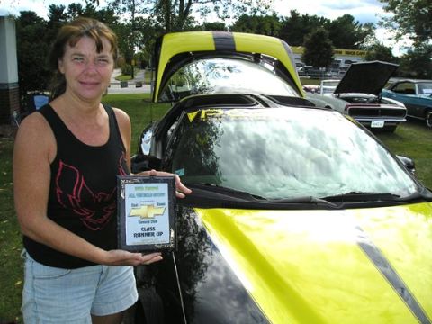1994 Pontiac Trans Am - A woman proudly displays her car's award at an outdoor car show.