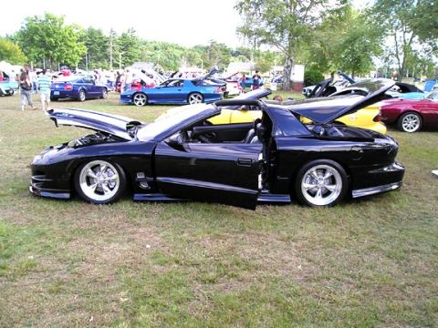 1994 Pontiac Trans Am - A black Pontiac Firebird is displayed with its hood and doors open at an outdoor car show.