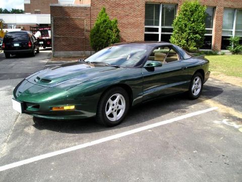 1994 Pontiac Trans Am - A green coupe is parked in a lot with a brick building in the background.