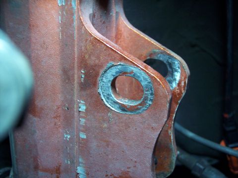 1995 Ford Probe - Close-up view of a red metal bracket two circular mounting holes.
