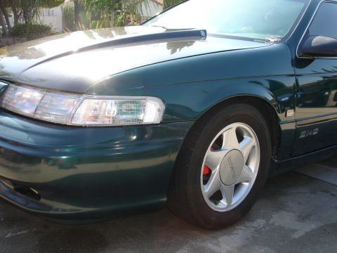 1993 Ford Taurus - Front passenger side view of a 1993 Ford Taurus, showing the wheel and headlight assembly.