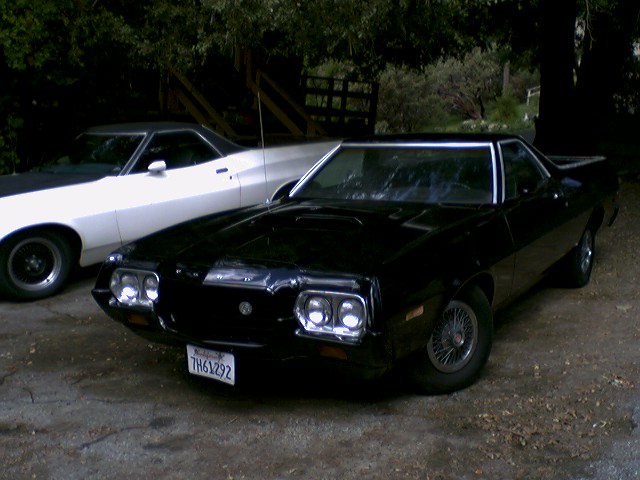 Black coupe utility with wire wheels parked next to a white one. License plate TH61292