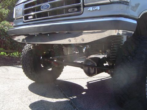 1989 Ford Bronco - Close-up of a gray Ford truck's front end, showing the grille, bumper, and suspension components.