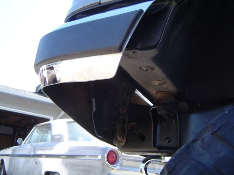 1989 Ford Bronco - Close-up of chrome bumper trim, with a vintage car visible in the background.