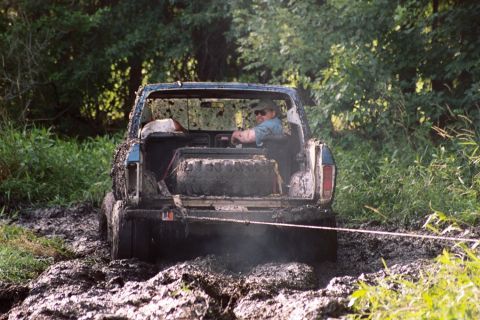 1979 Ford Bronco - Muddy 1978 Ford Bronco is stuck in a muddy off-road trail with a driver inside.