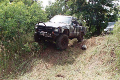 1979 Ford Bronco - A Toyota pickup truck navigates an off-road trail, with another vehicle visible behind it.