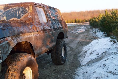 1979 Ford Bronco - This heavily rusted 1979 Ford Bronco is parked on a muddy, snowy dirt road in a wooded area.