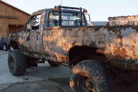 1979 Ford Bronco - This heavily mud-caked pickup truck, likely from the early 1980s, is shown from a 3/4 front angle.