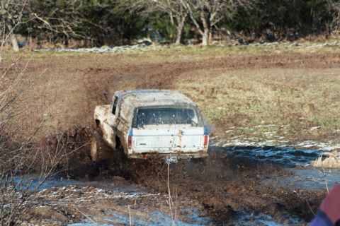 1979 Ford Bronco - A white Ford Bronco navigates a challenging muddy terrain during an outdoor event.