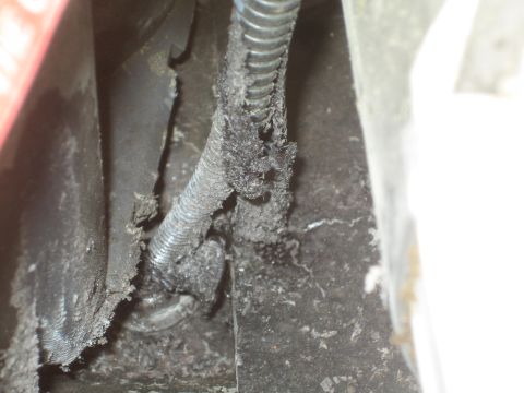 1990 Ford Bronco - close-up of a heavily soiled coiled metal flex conduit and surrounding grease-caked black automotive parts.