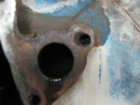 1986 Ford Bronco - A close-up view of a rusty engine component, likely from an older vehicle, with remnants of blue paint visible.