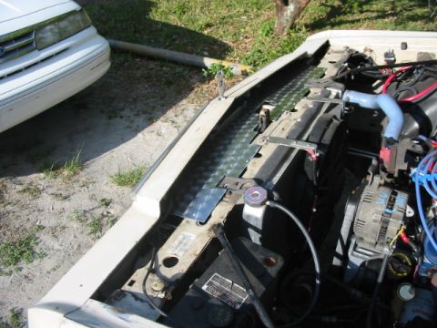 1985 Ford LTD Crown Victoria - Engine bay of a 1985 Ford Crown Victoria LTD, showing the radiator and alternator. A second vehicle is in the background.