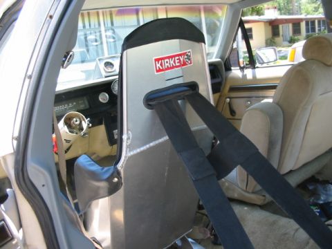 1985 Ford LTD Crown Victoria - The interior of a vehicle shows a racing seat with a Kirkey sticker and a racing harness.