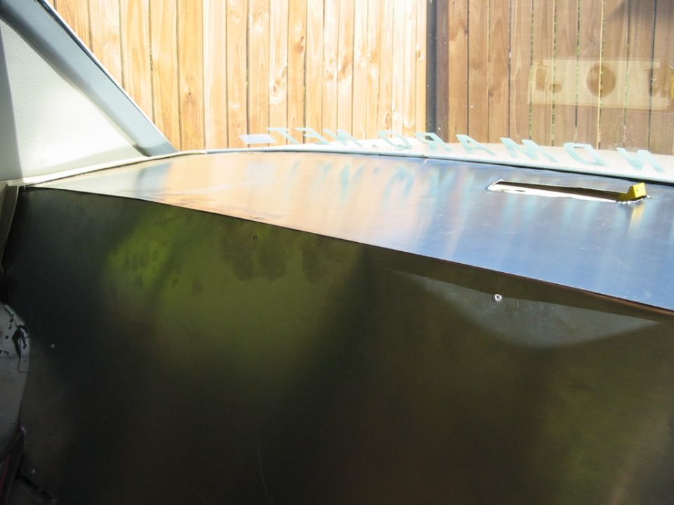 Interior view of a car dashboard with a metal finish and a partial view of the windshield frame