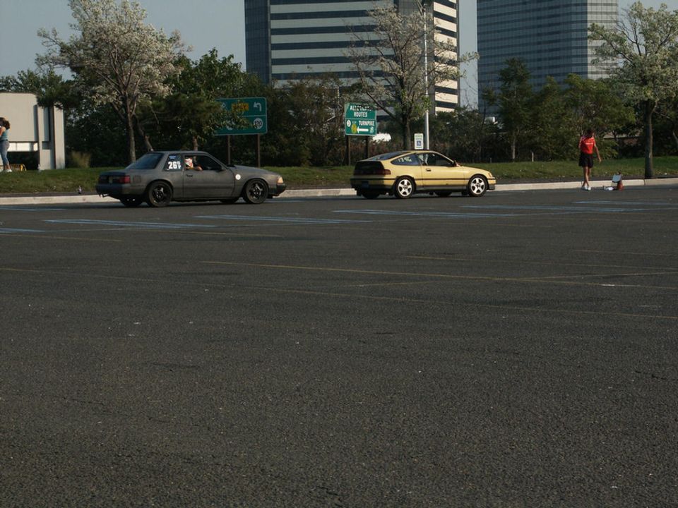 Gray sedan with number 261 on door and yellow hatchback parked on asphalt