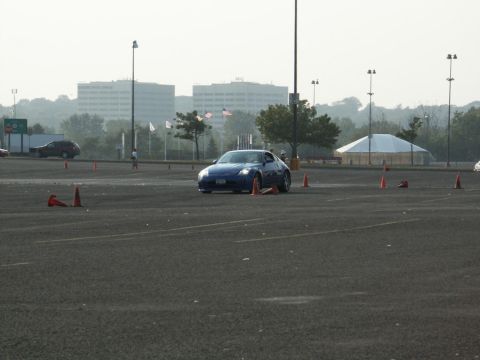 2001 Mercury Grand Marquis - A blue sports car is seen maneuvering through a cone course on a paved lot with buildings in the background.